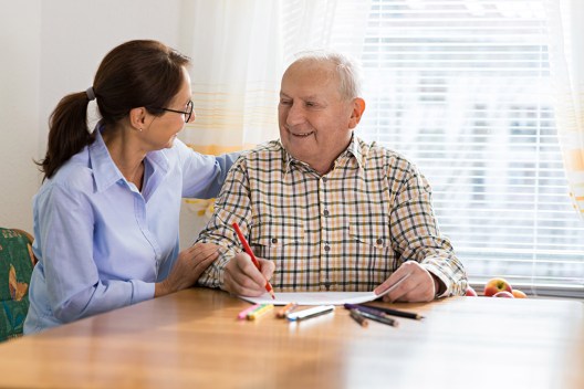 Elderly man writing and coloring as part of occupational therapy